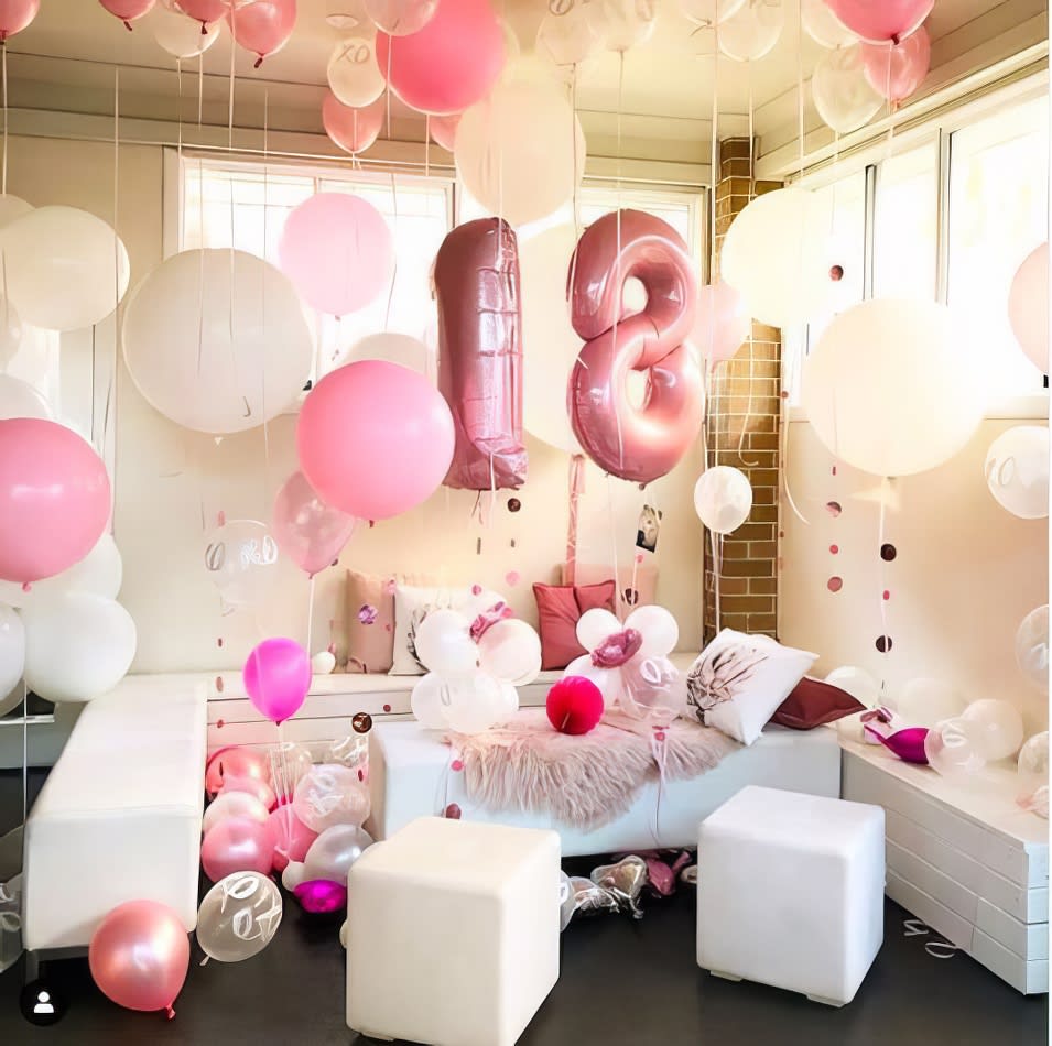 A room filled with pink and white balloons, enhanced with a white ottoman cube hire.