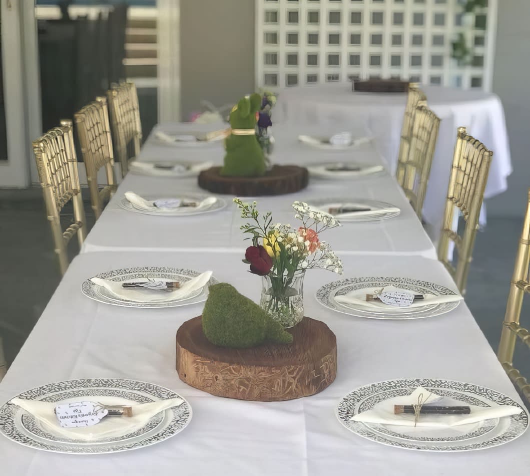 A white tablecloth elegantly drapes over a large trestle table, creating the perfect setup for a dinner party.