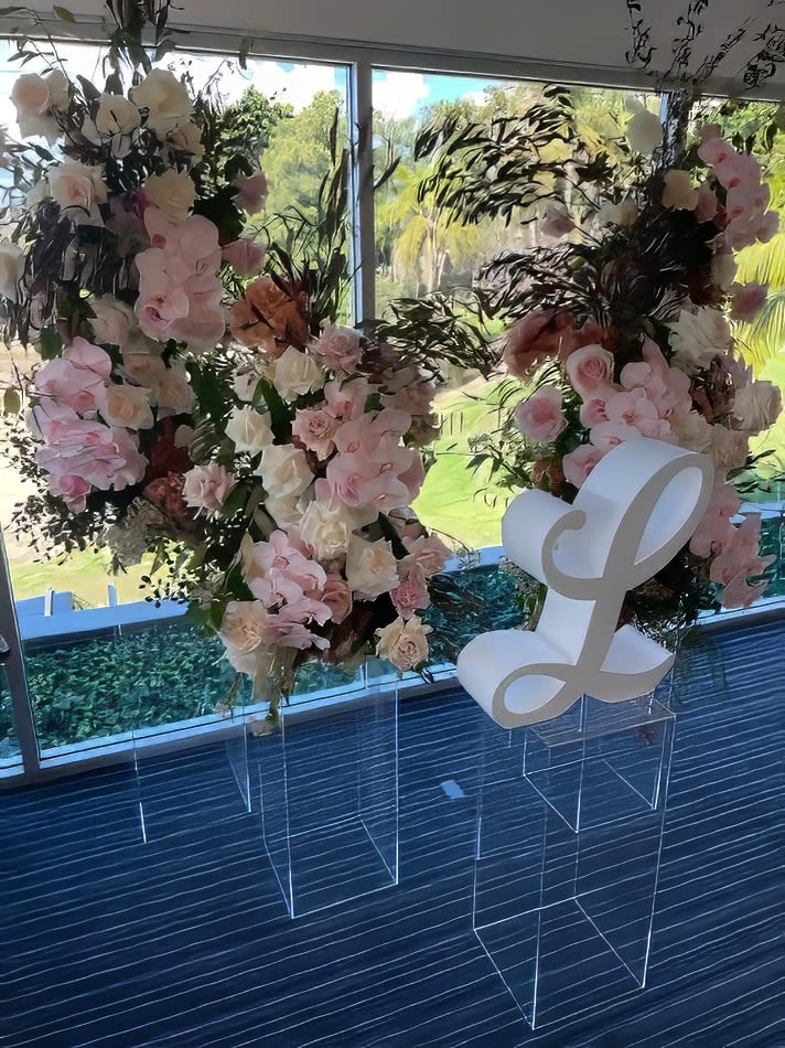 A flower arrangement with a letter l in the middle of a room, showcased on a Clear Acrylic Plinth.