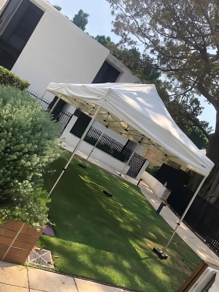 A 3mx6m Pop Up Marquee with a white roof set up on a lawn in front of a house.