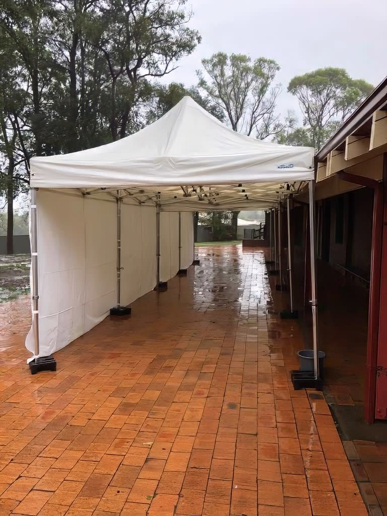 A 4mx8m white tent is set up in a rainy courtyard, featuring walls on 3 sides.