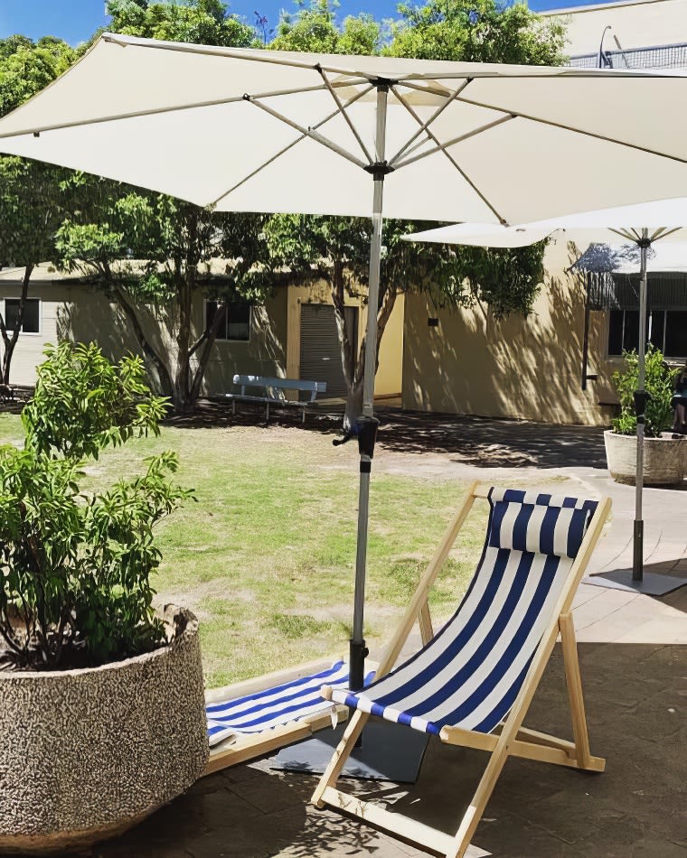 A blue and white striped lounge chair under a market umbrella.