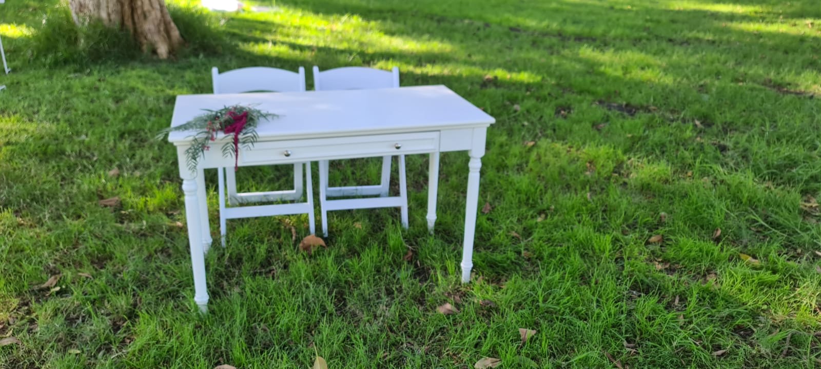 A white vintage-style table and chairs in the grass.