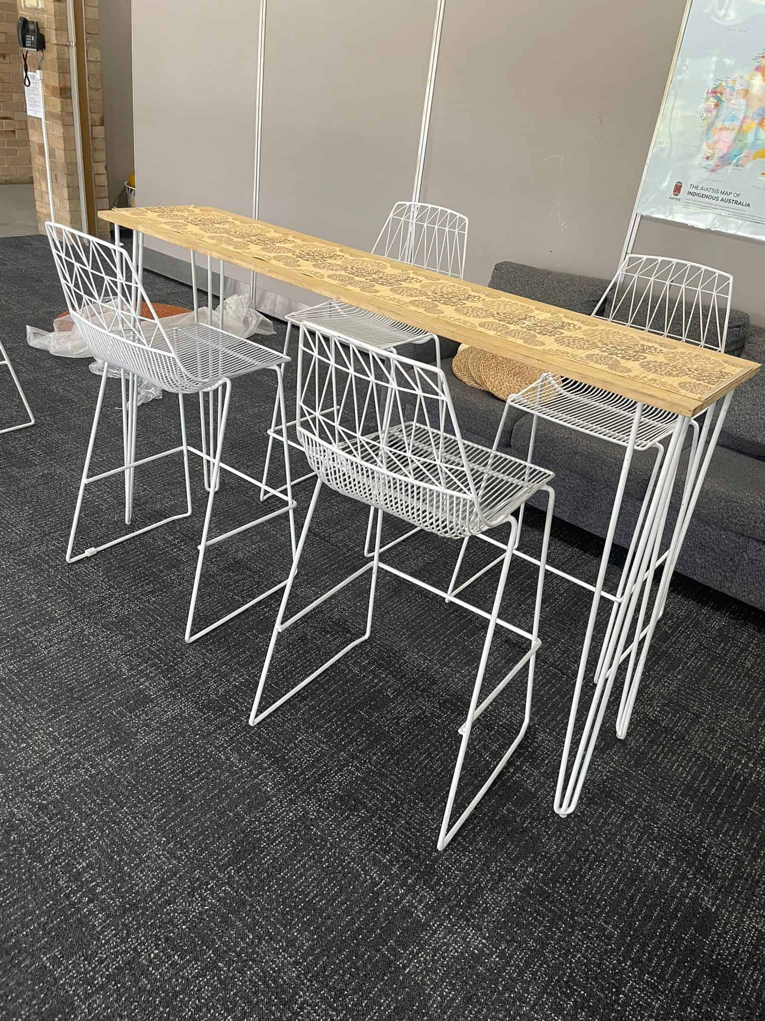 A white hairpin high bar table with timber top in an office.