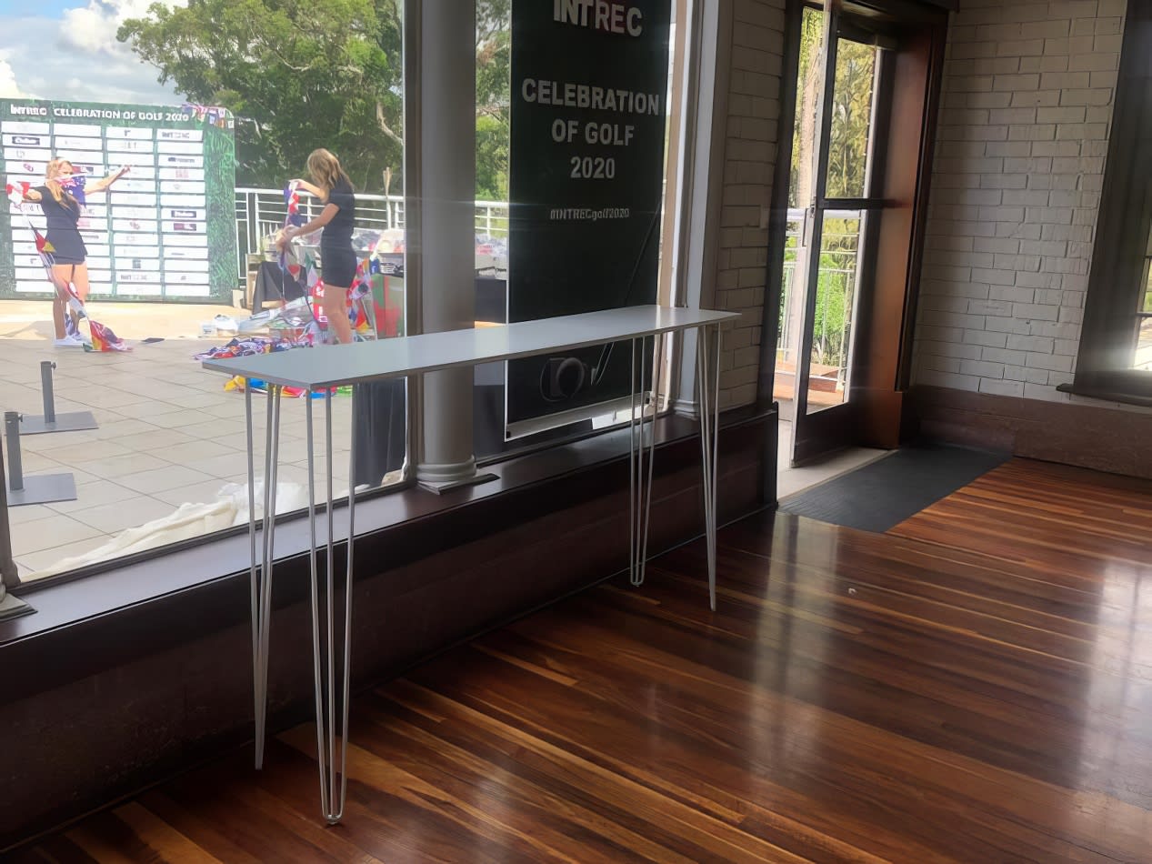 A high bar table with a white top placed in front of a window in a building.