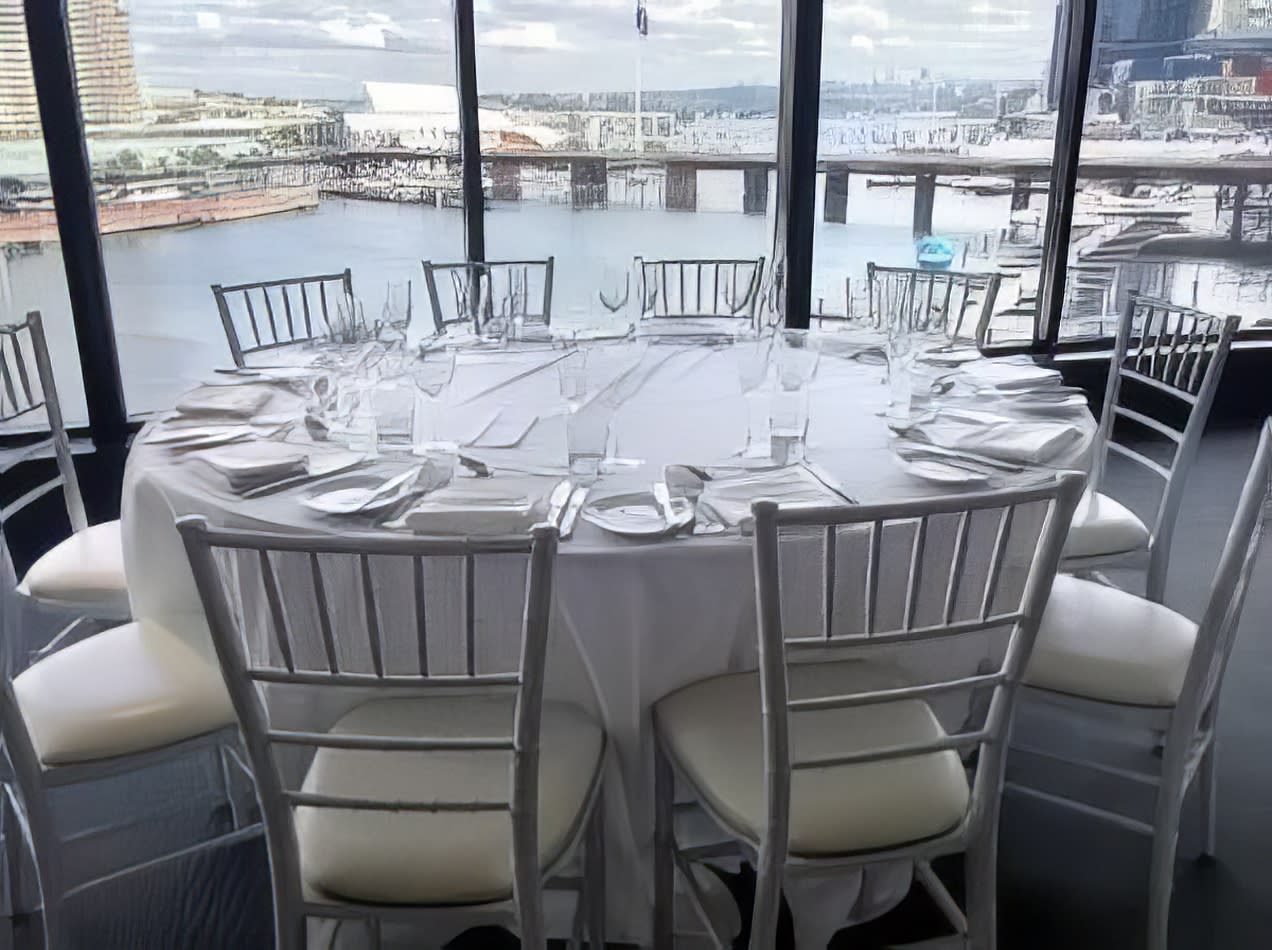 Round timber table hire with white chairs and a view of the city.