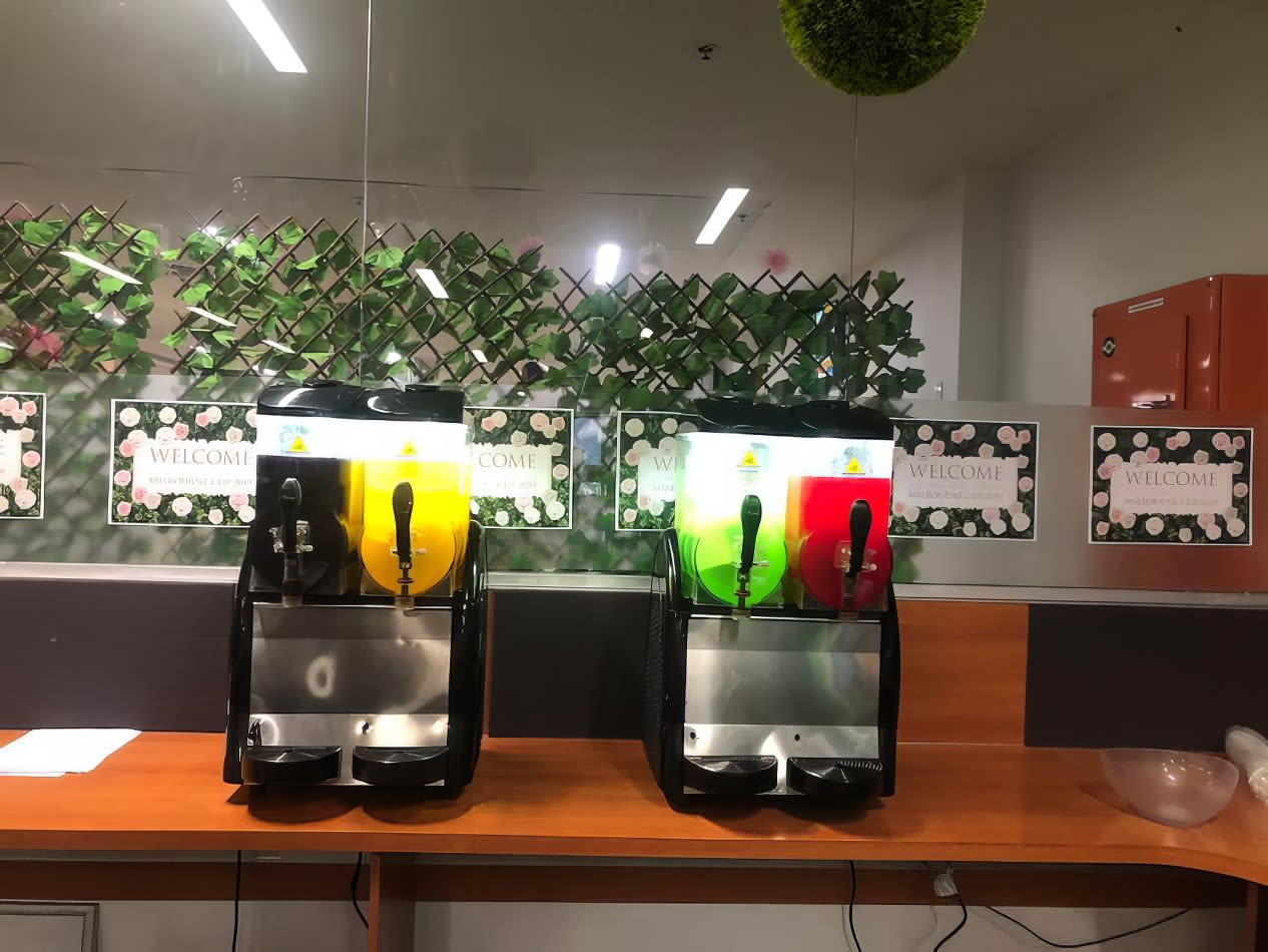 Two juice dispensers, one being a Slushie Machine from Package 2, with plants on them.