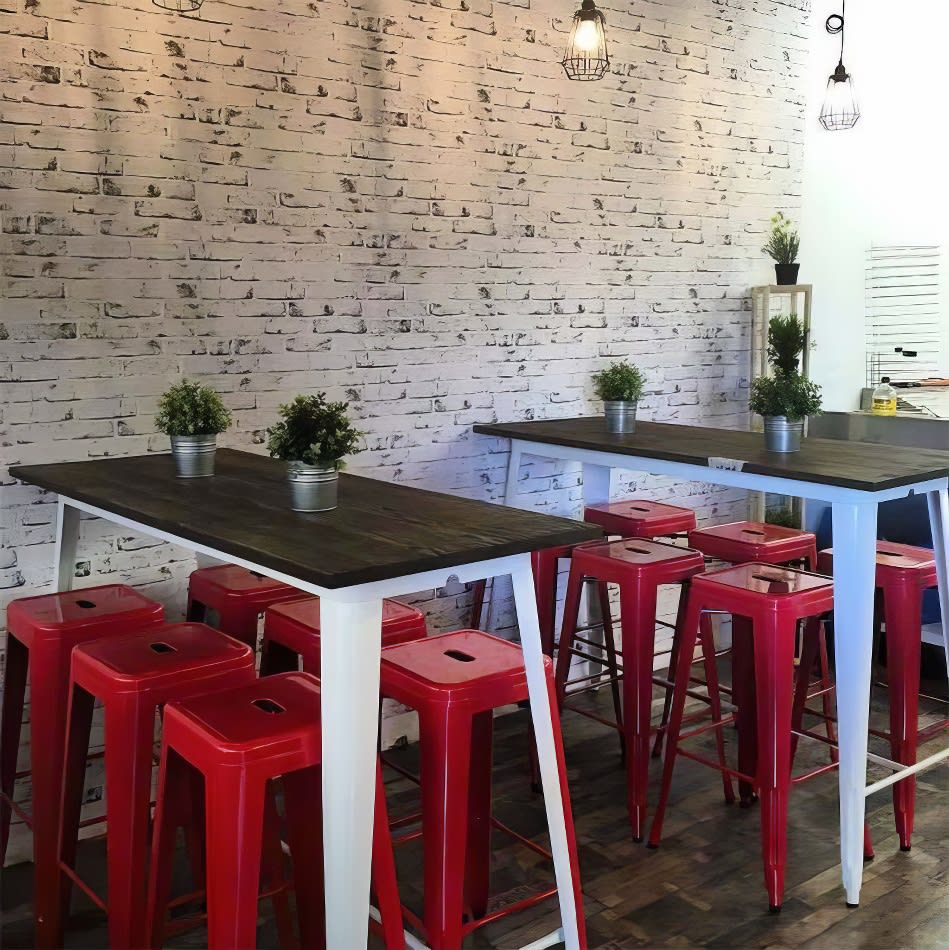 A restaurant with red Tolix stools and a brick wall.