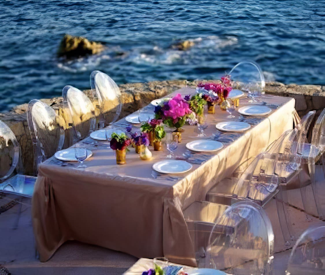 A table set up on a cliff overlooking the ocean, enhanced with Victorian Ghost Chair Hire.