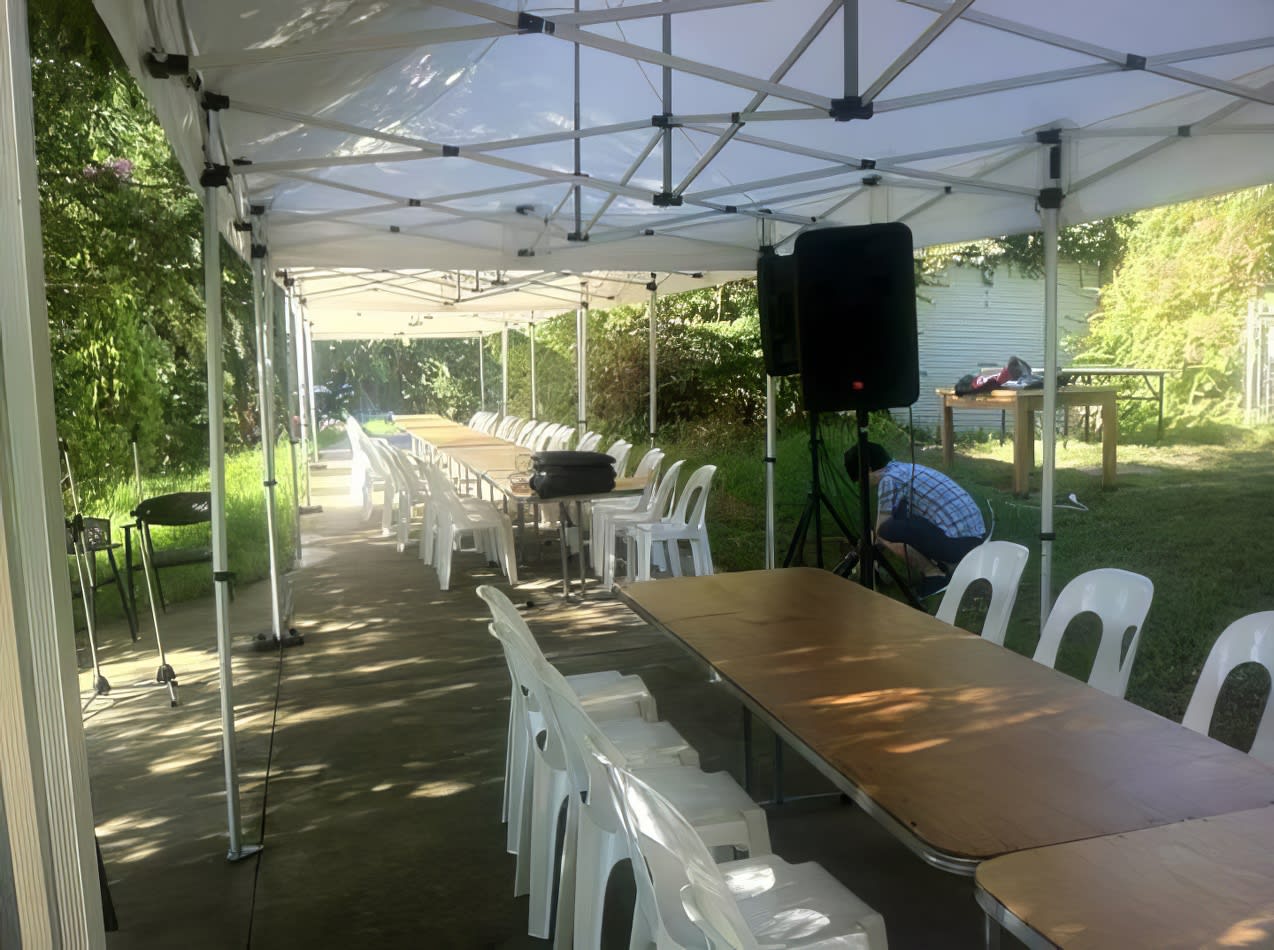 A backyard set up with timber trestle tables and chairs for hire.