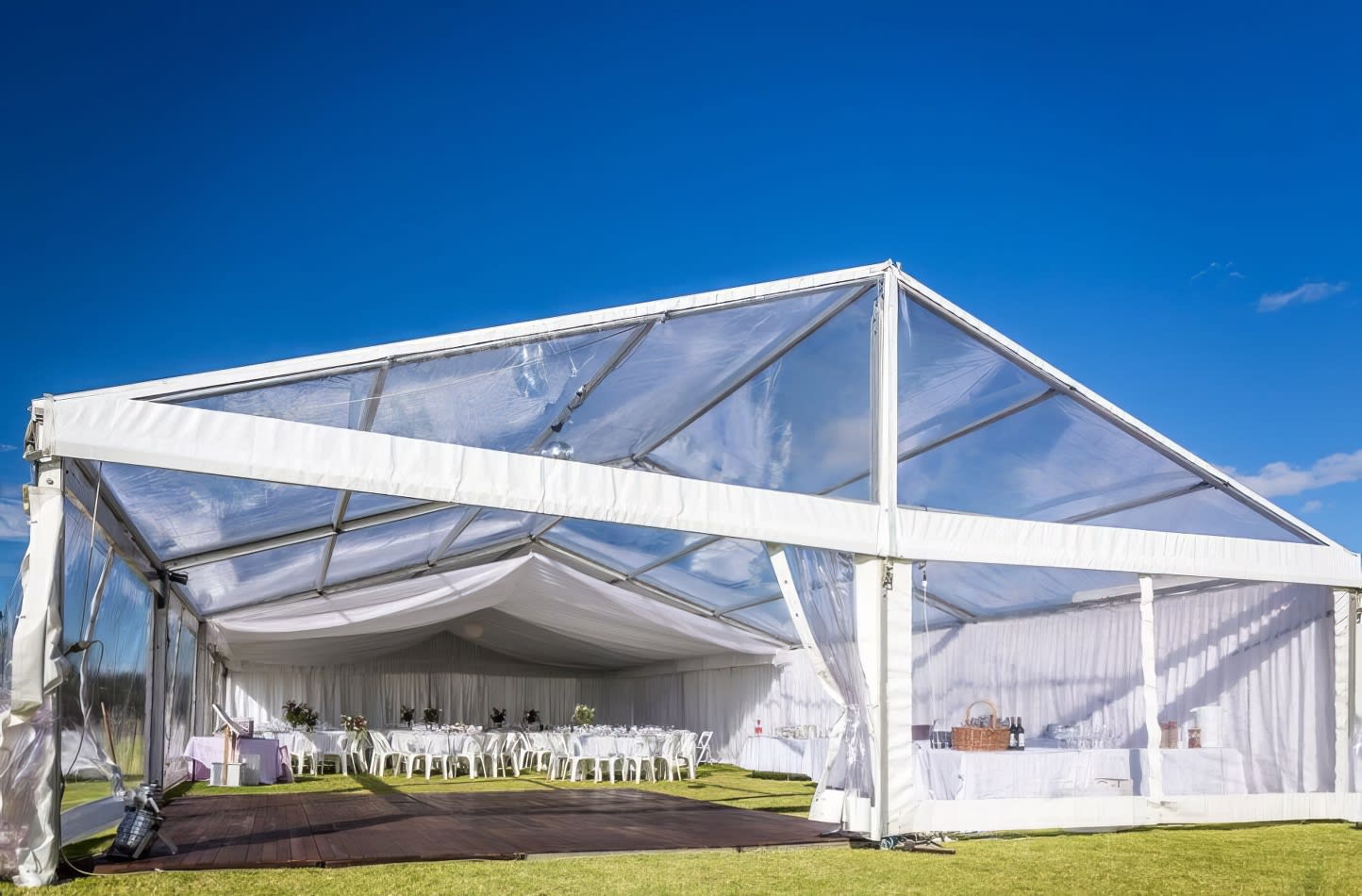 A white framed marquee set up on a grassy field.