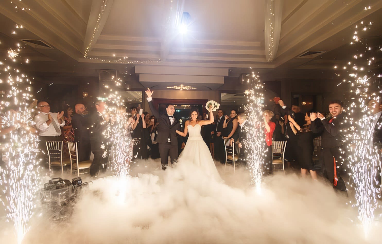 A bride and groom walk down the aisle with sparklers in the air, enhanced by a professional dry sparkler hire operator.