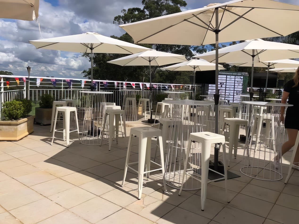 A white table and chairs on a patio with market umbrellas.