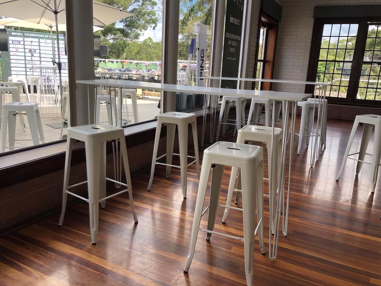 In a trendy restaurant, elegant white stools gently punctuate the warm wooden floor.