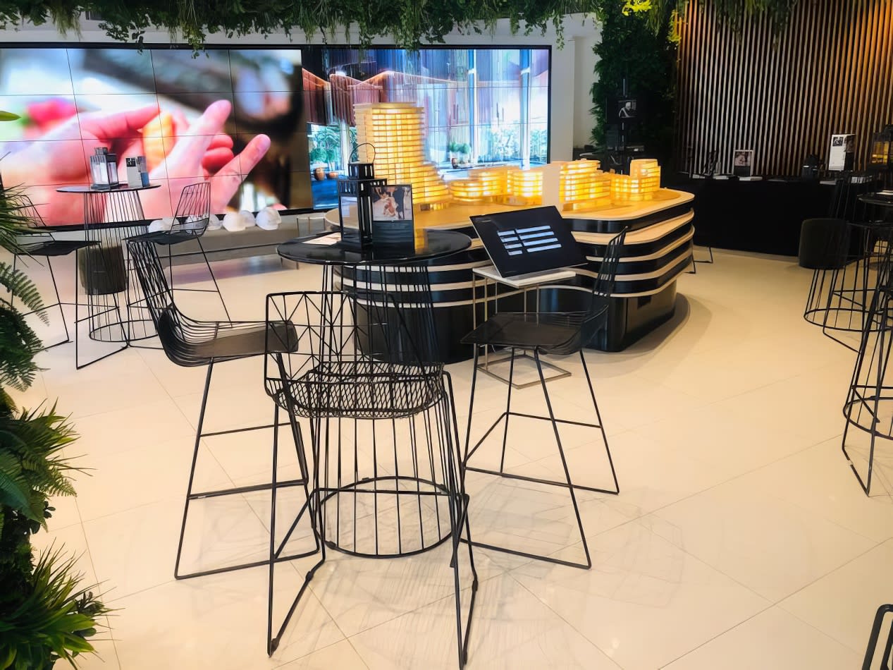 The interior of a coffee shop with black stools and plants, featuring black wire cocktail table hire.