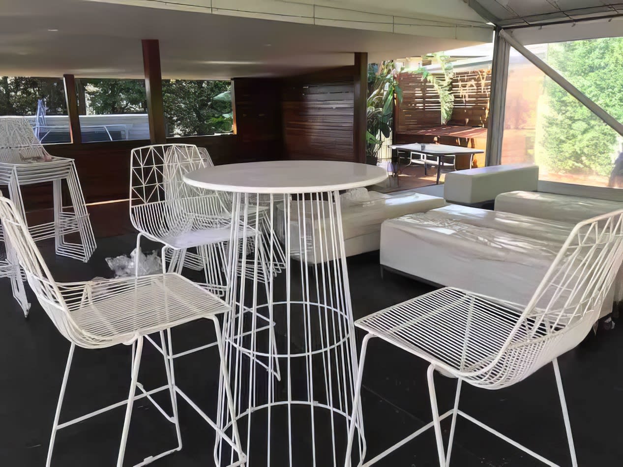 A white table and chairs in an outdoor setting for hire.