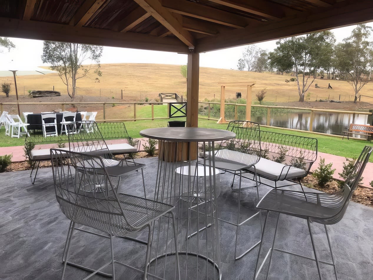 A patio with a view of a pond, featuring a table and chairs.