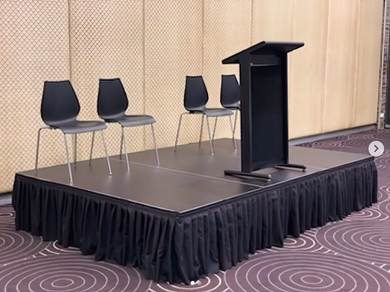 A podium stand with four black executive chairs.