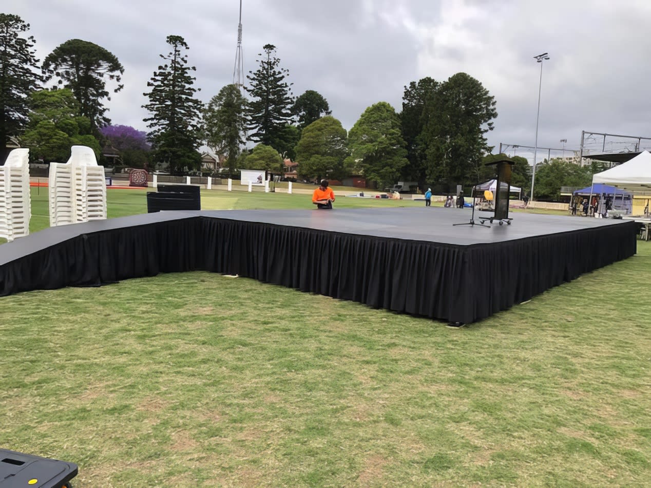 A grassy area transformed into a stage, complete with microphone stand hire.