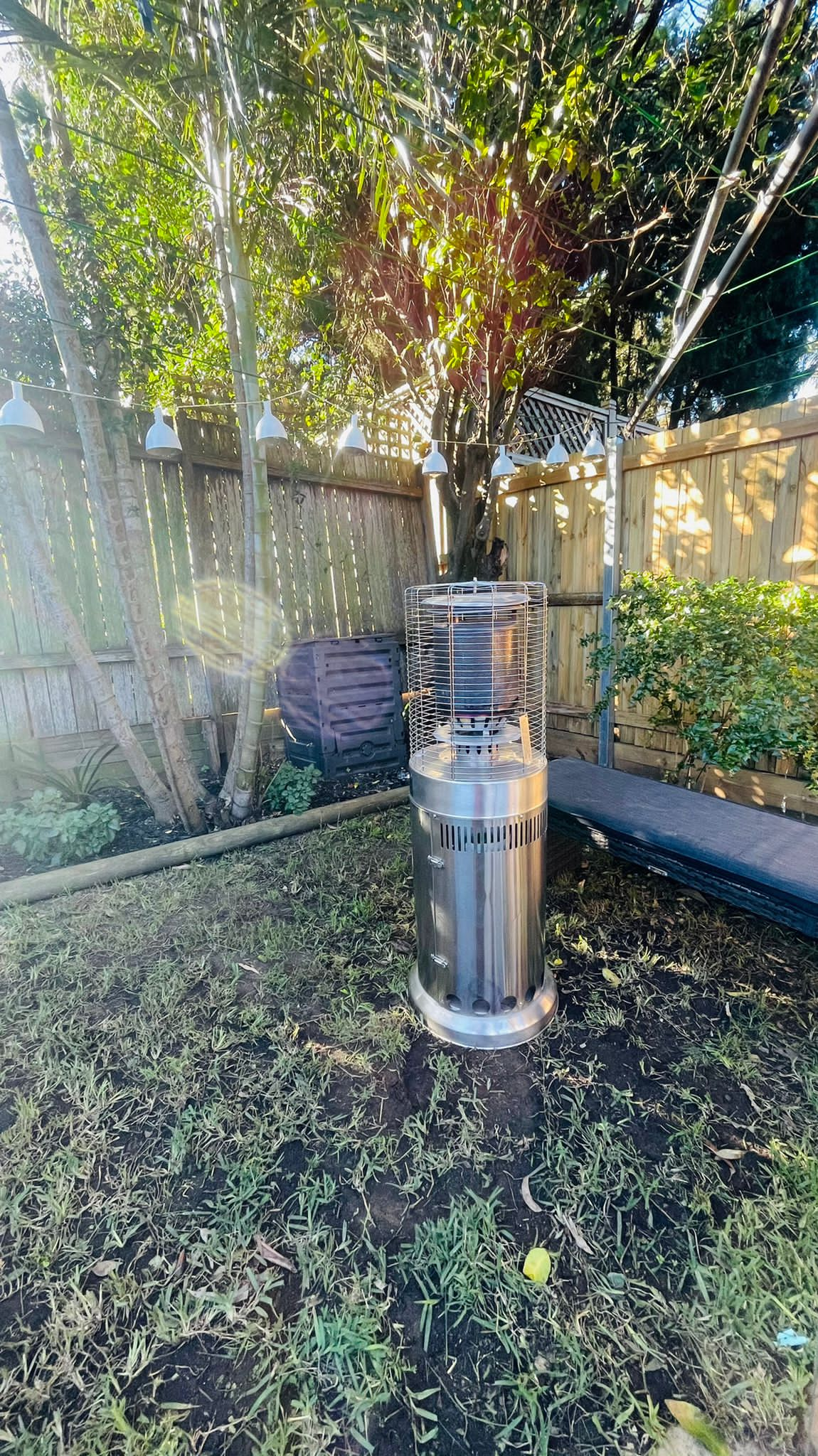 A stainless steel barbecue in a backyard, accompanied by a package of 3 area heater hires with gas bottles.