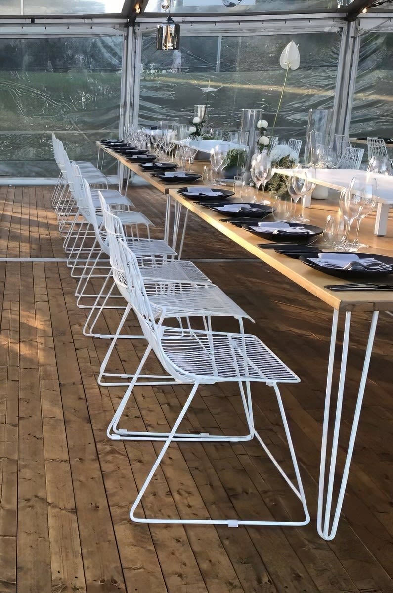 A white table and chairs are set up in a tent for White Chair Hire.