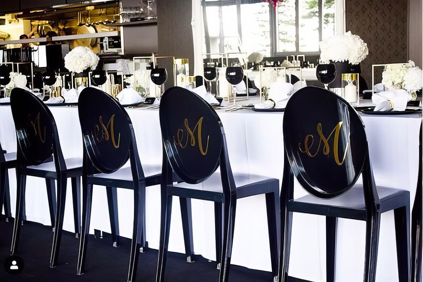 A table with black and white chairs and a Victorian-inspired monogrammed tablecloth.