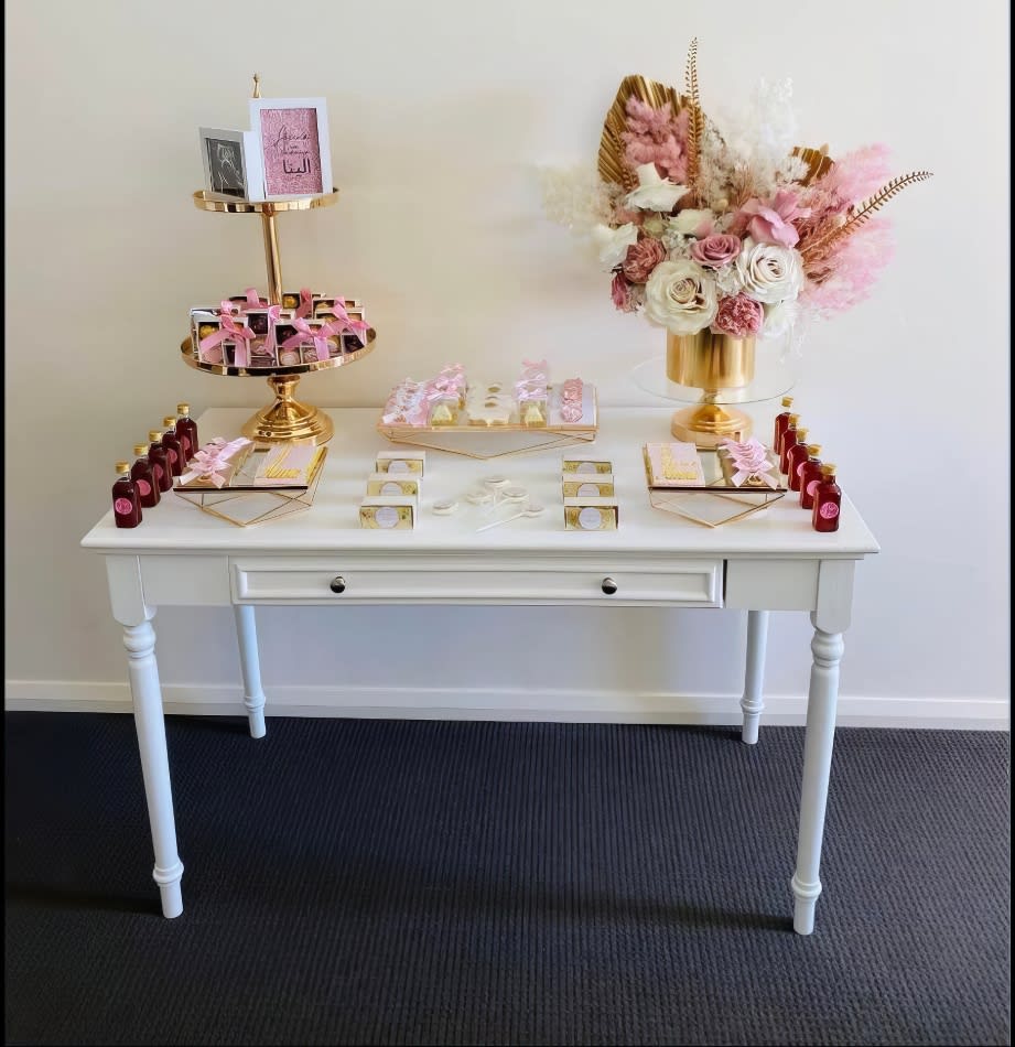 A white vintage-style table with pink and gold decorations available for hire.