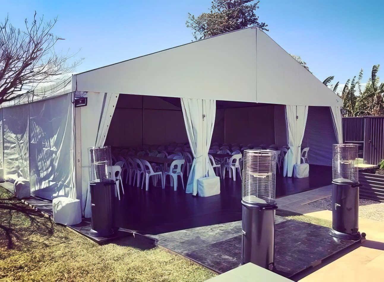 A white tent set up in a backyard, illuminated with LED floodlights hired for the occasion.