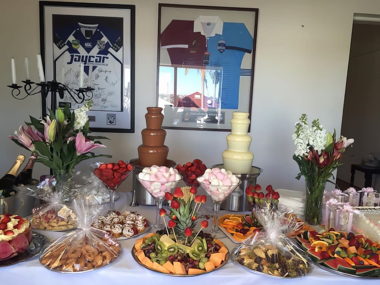 A table adorned with an abundance of delectable food and desserts, accompanied by two small commercial fountains.