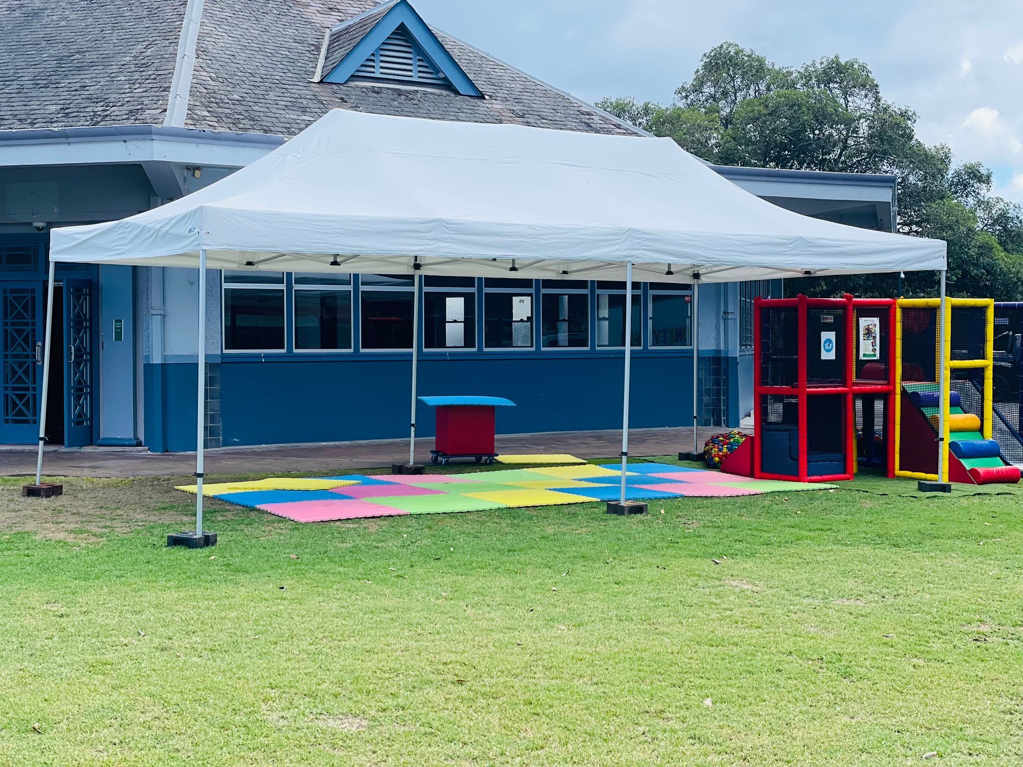 A white tent, specifically a 4mx8m Pop Up Marquee with a white roof, is set up in front of a building.