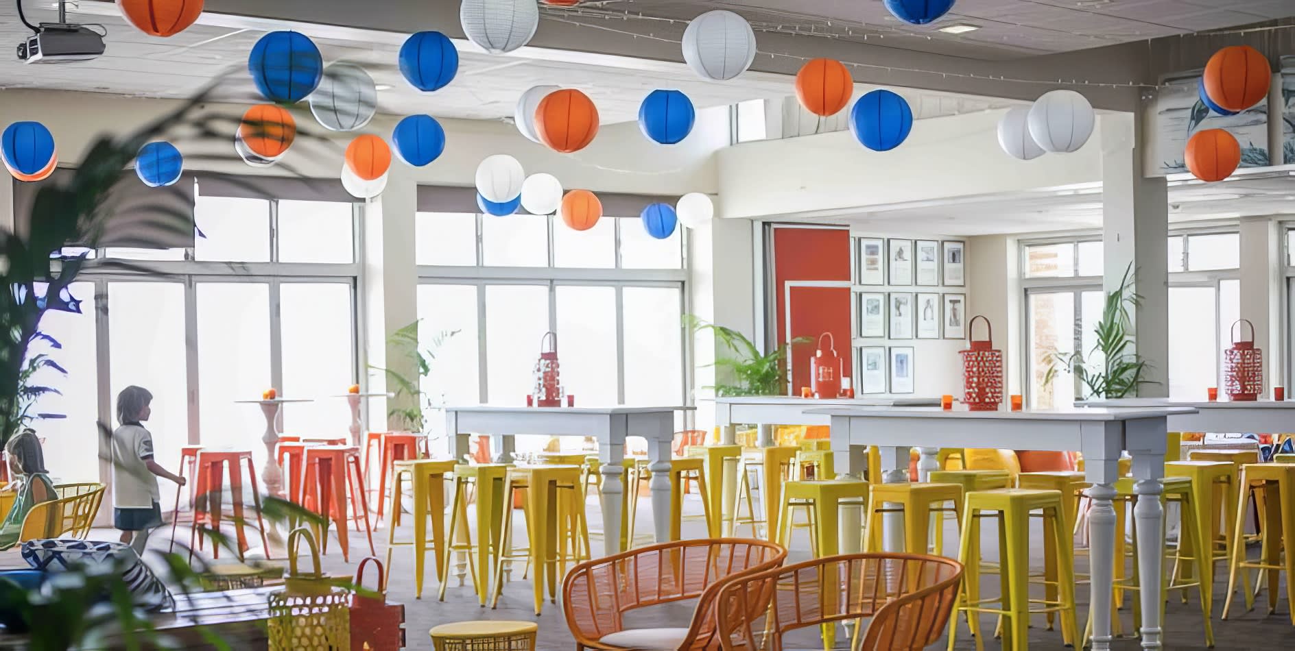 A room filled with orange Tolix stools and colorful balloons.