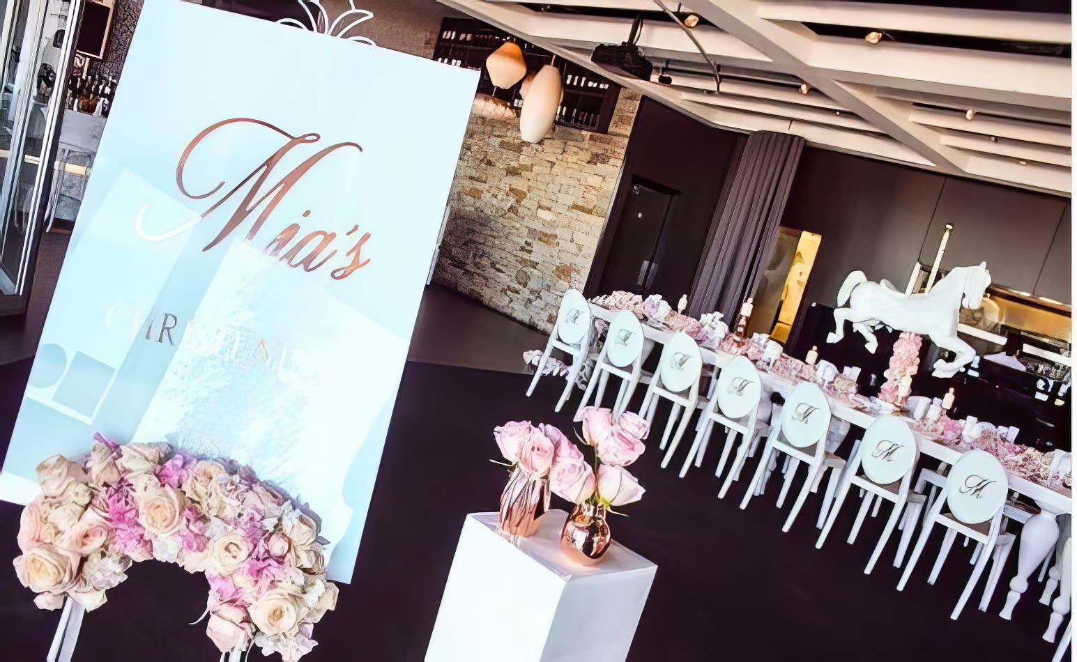 A wedding reception set up with white Victorian chairs and pink flowers.