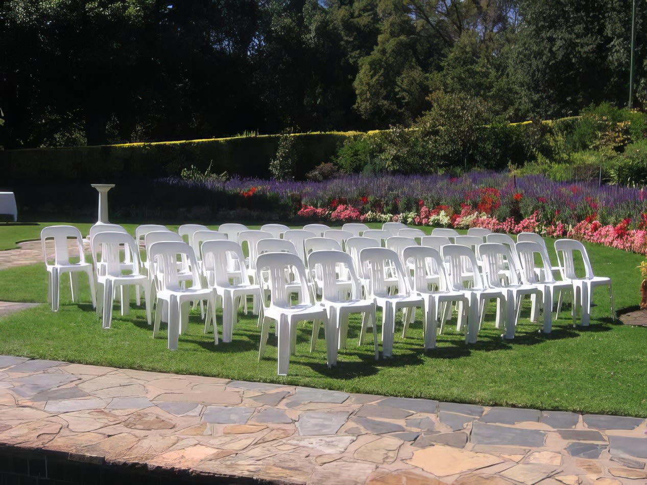 A row of white plastic chairs in a garden.