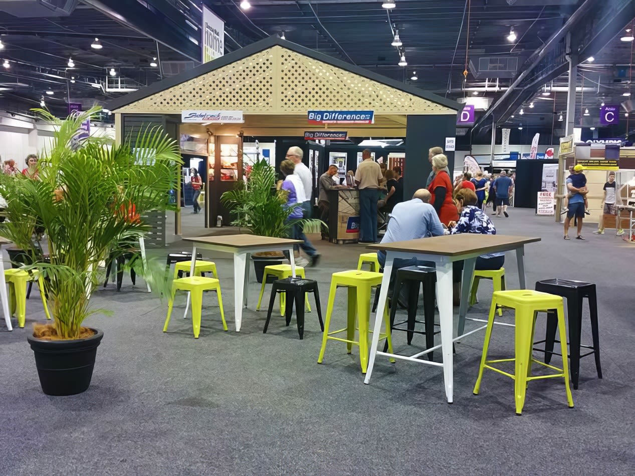 A booth at a trade show with tables and Lime Tolix stool hire.