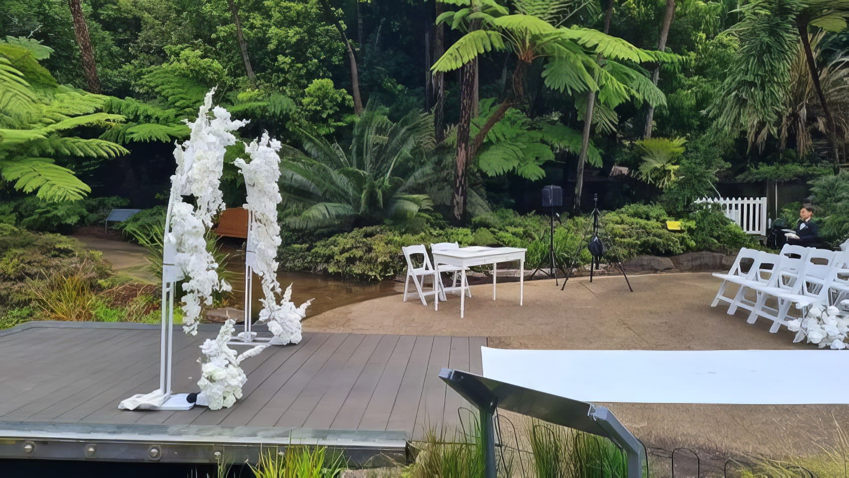 A stunning wedding ceremony set up in a zoo garden, complete with elegant white vintage style tables for hire.