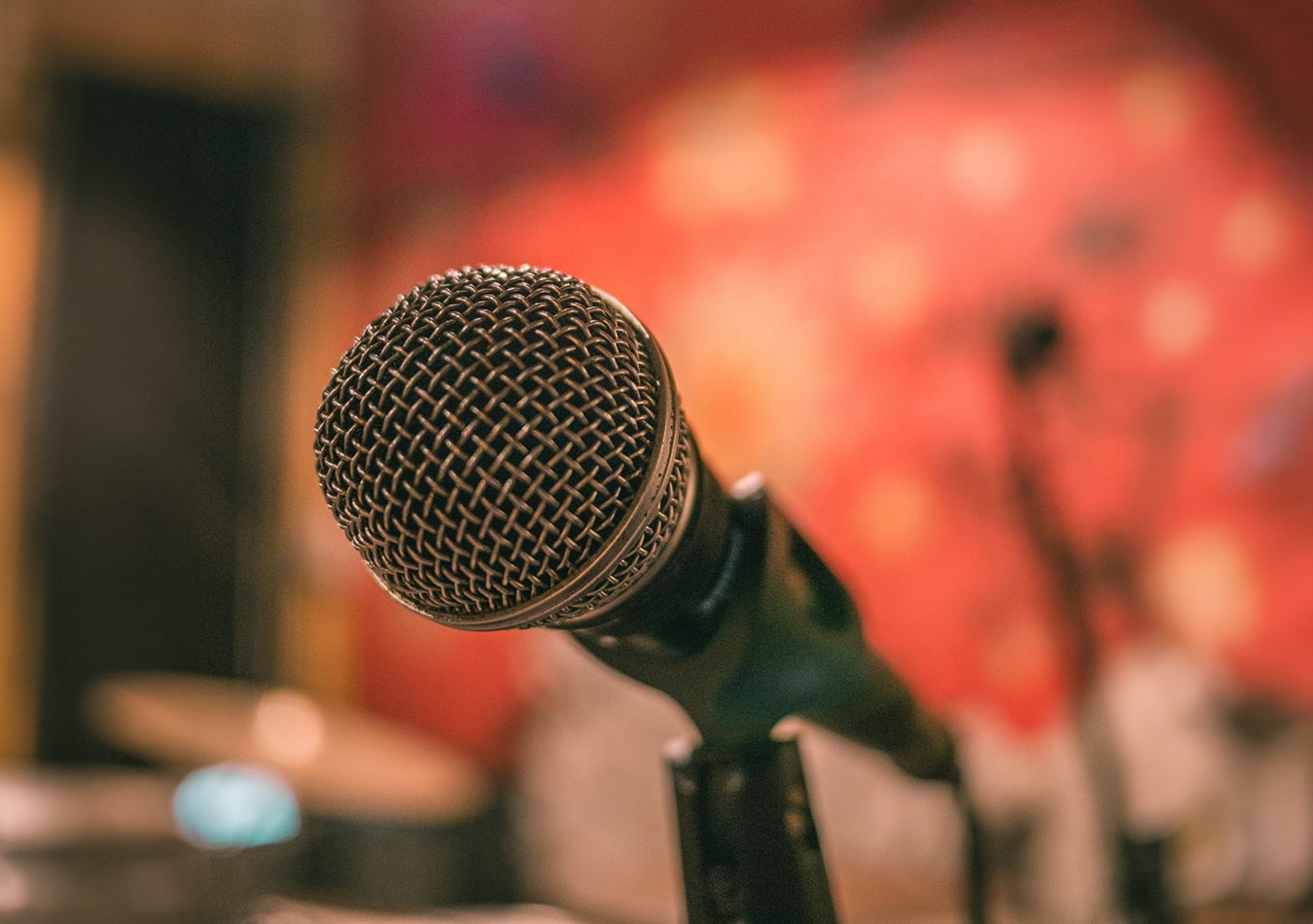 A corded microphone in front of a red wall in a recording studio.