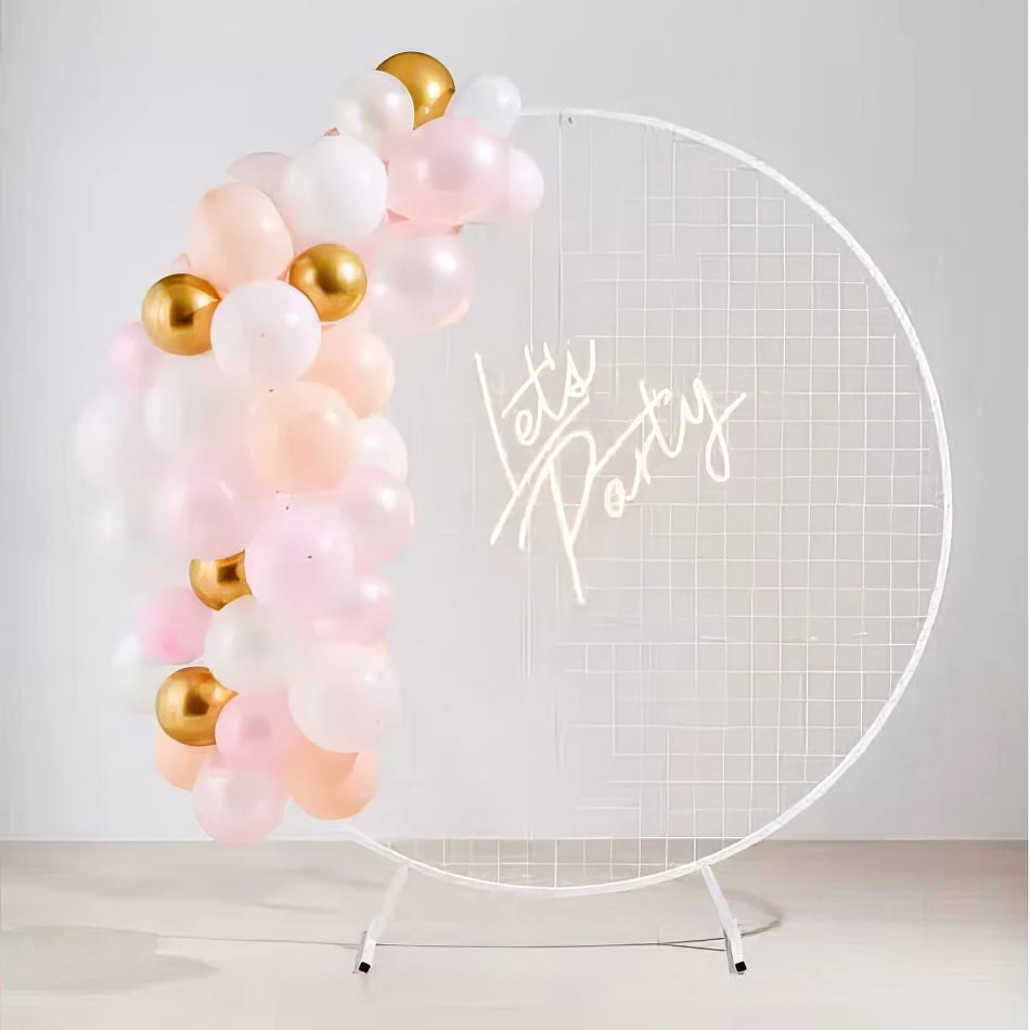 A let's party sign adorns a pink and gold balloon arch.