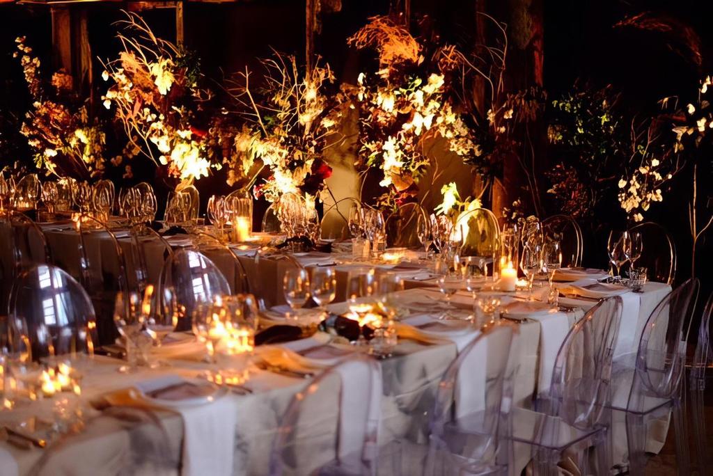 A table set up with clear chairs and flowers for a party