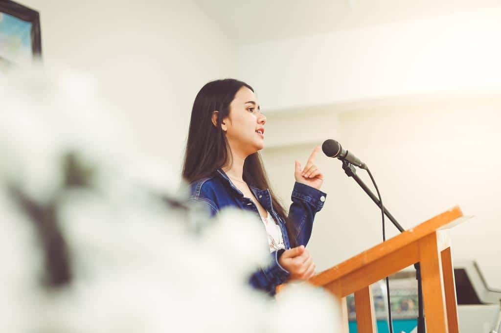 Woman speaking through corded microphone