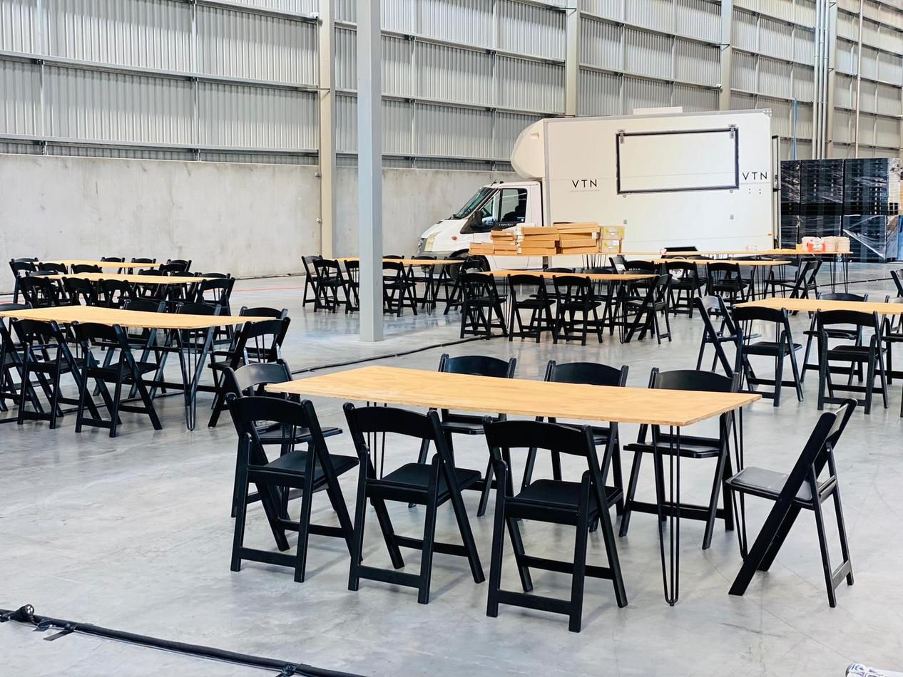 A large warehouse with black padded folding chairs set up.