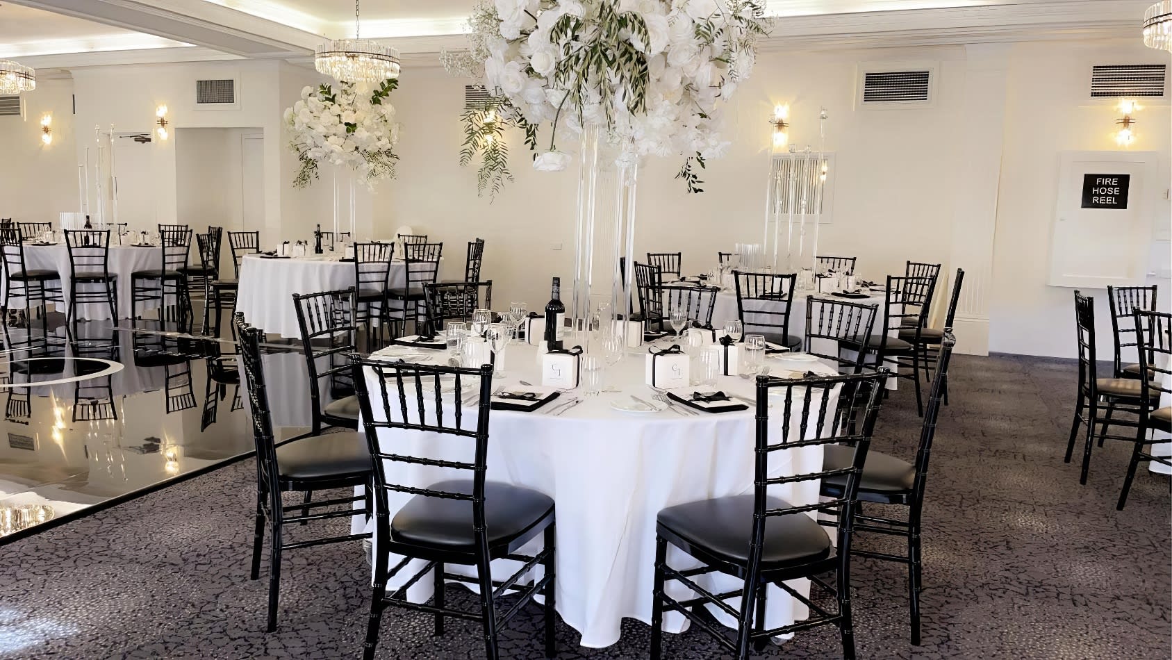 A black and white room with tables and Black Tiffany Chair Hire.