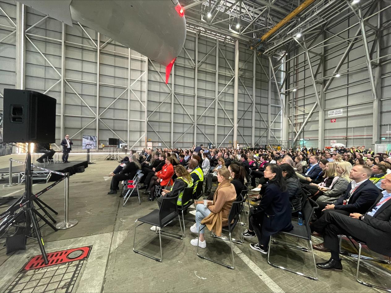 A large group of people attending a conference in a hangar.