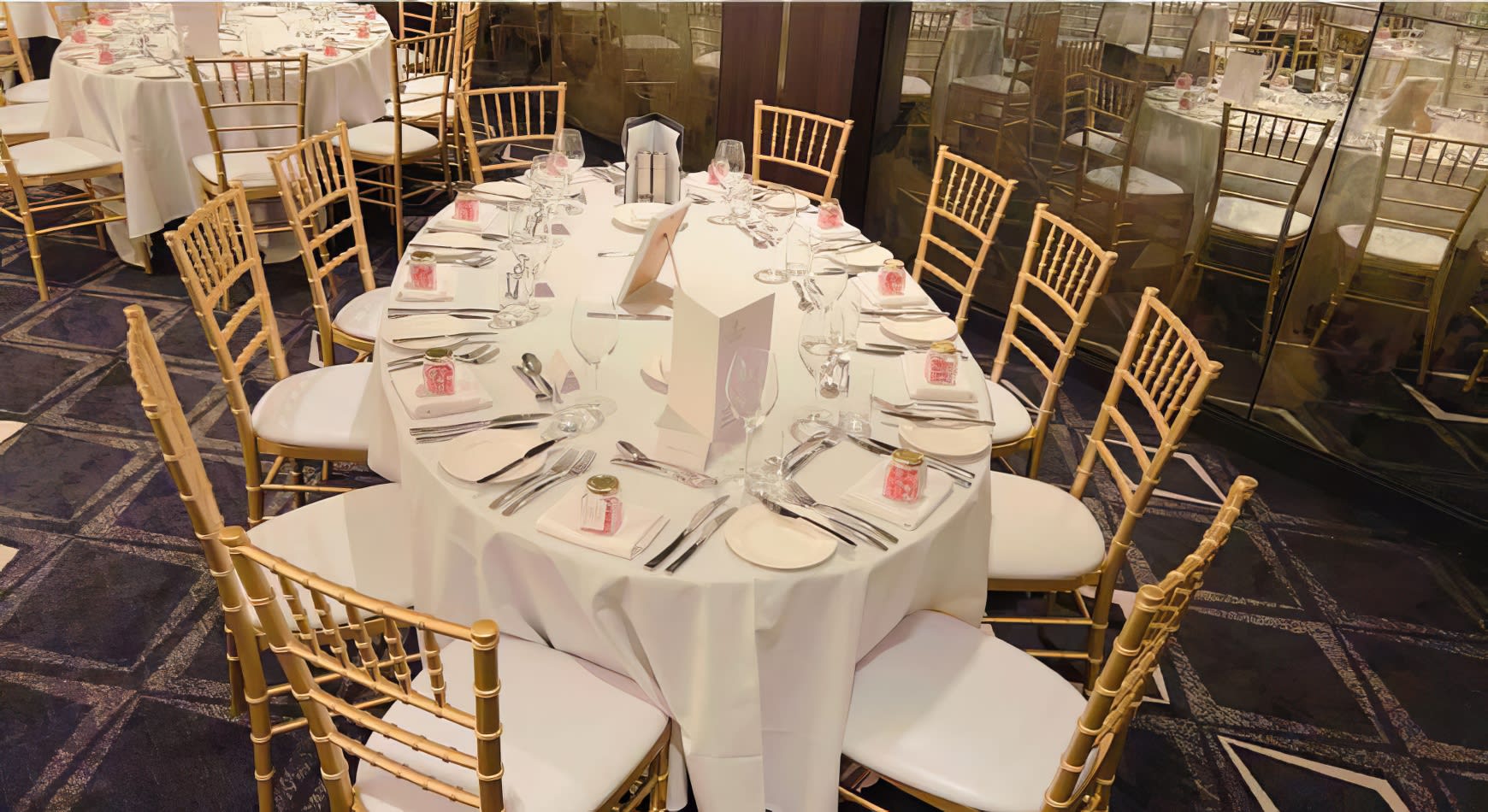 A room with tables and chairs, including Gold Tiffany Chairs, set up for a wedding.