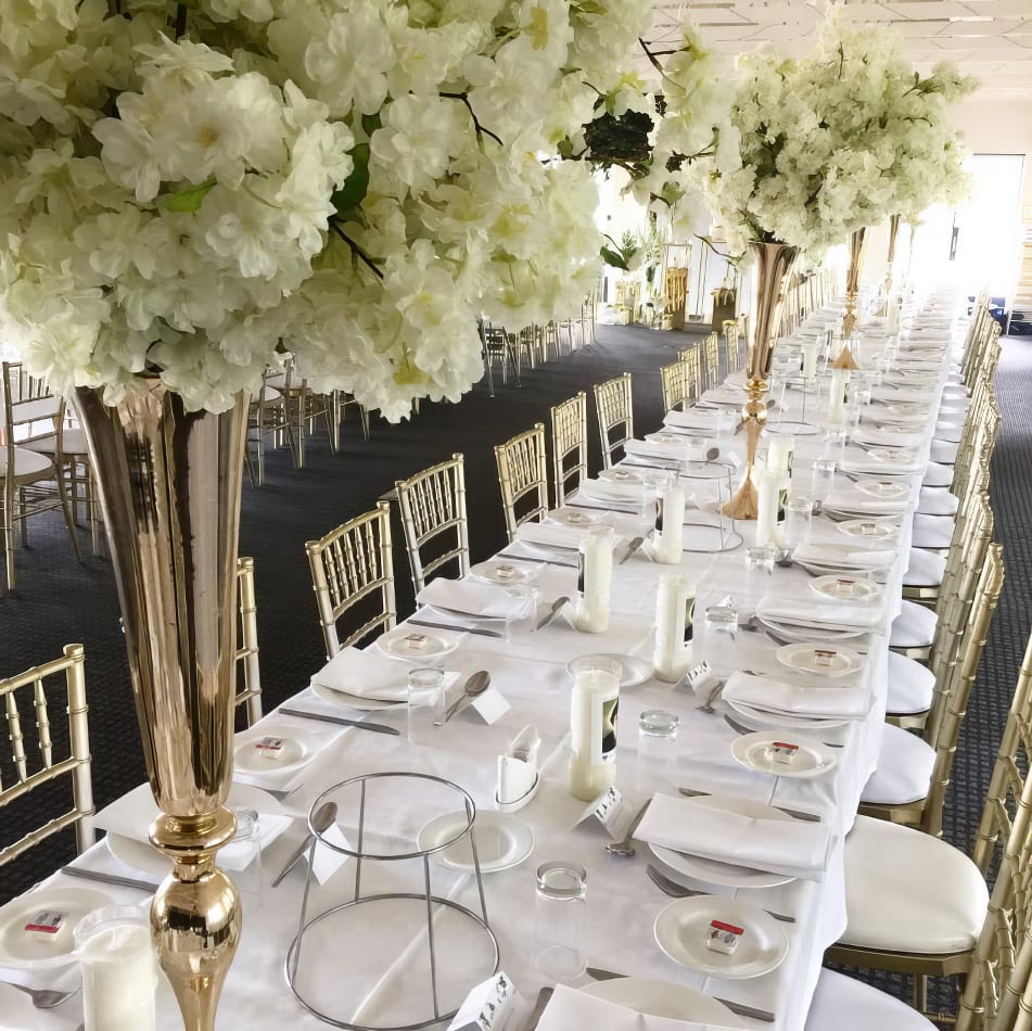 A long table adorned with beautiful white flowers arranged in elegant gold vases.