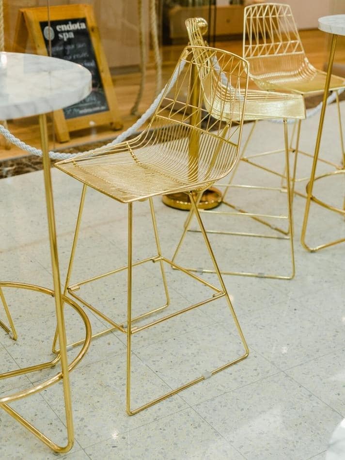 Gold bar stools with marble tops available for hire in store.