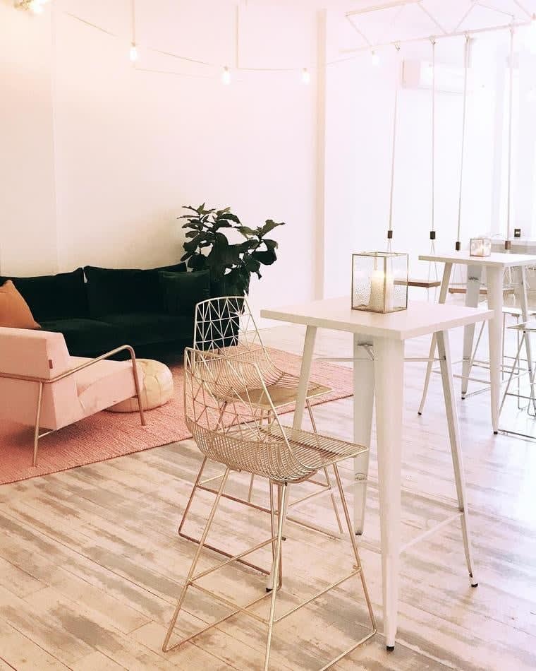 A pink and white room with a table, chairs, and a Gold Wire Stool.