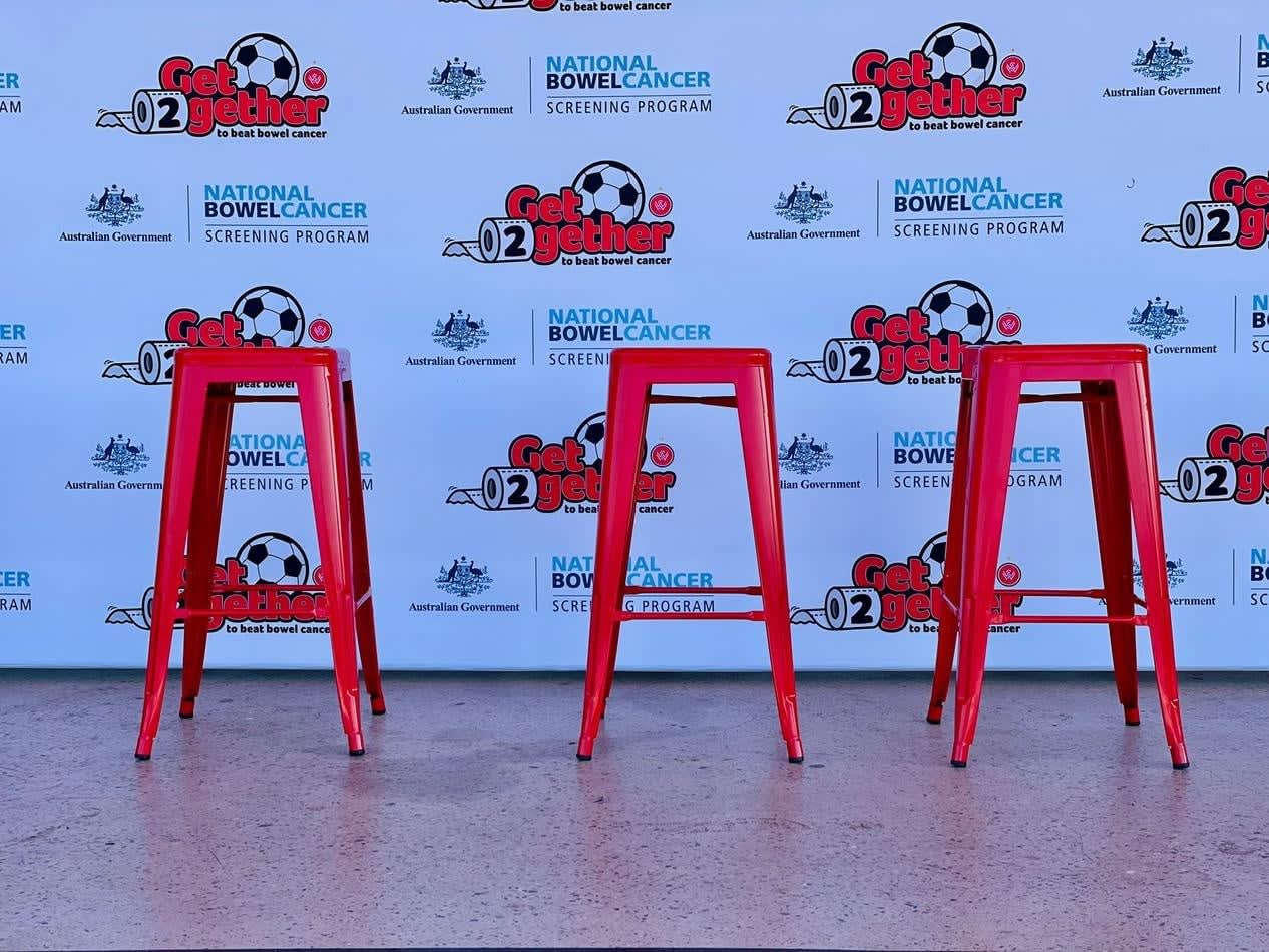 Three red Tolix stools in front of a banner.