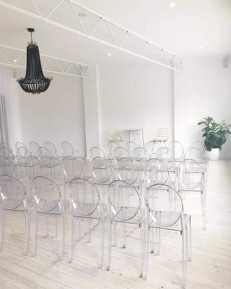 A room filled with Victorian ghost chairs and a chandelier.