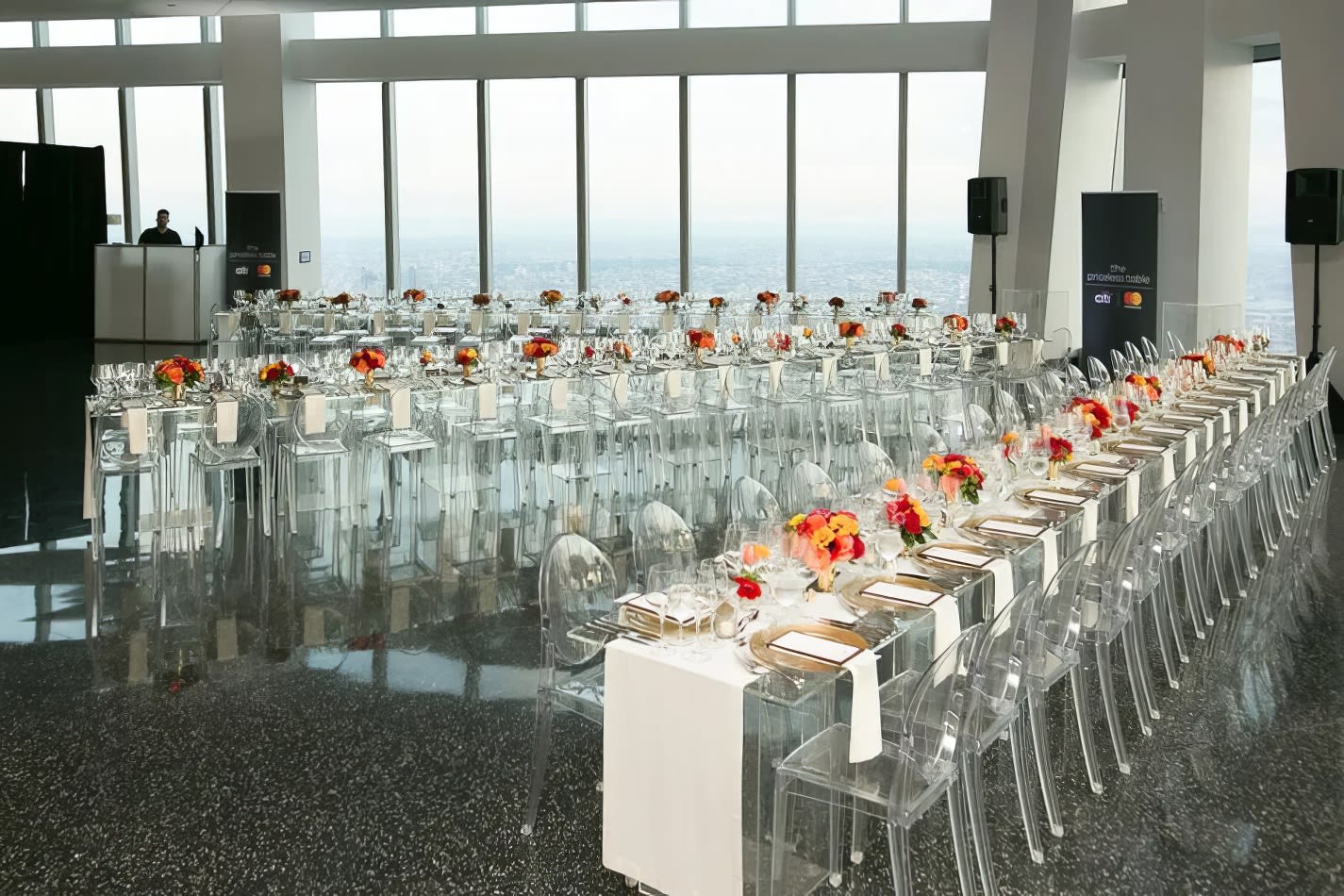 A long table is set up in a room with a view of the city, featuring Victorian Ghost Chair Hire.