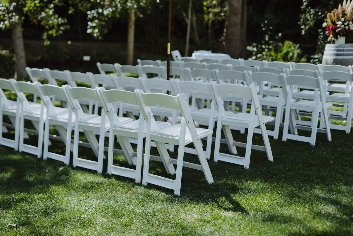 White folding chairs set up for a wedding ceremony, available for White Padded Folding Chair Hire.